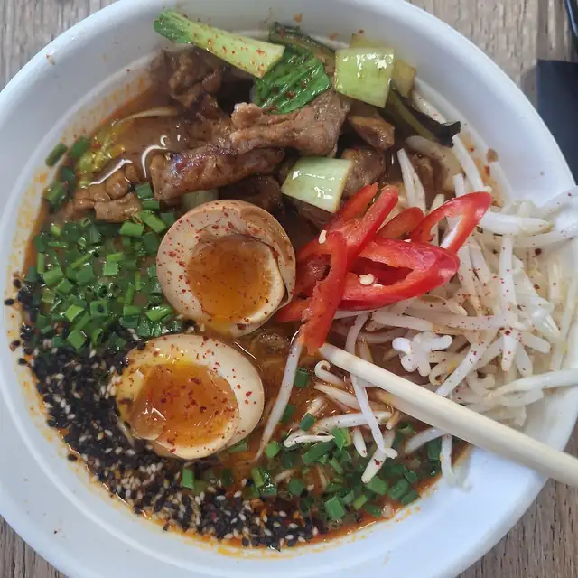 Ork Ramen z góry: jajka marynowane, wieprzowina, czerwona papryka i kiełki w białej misce